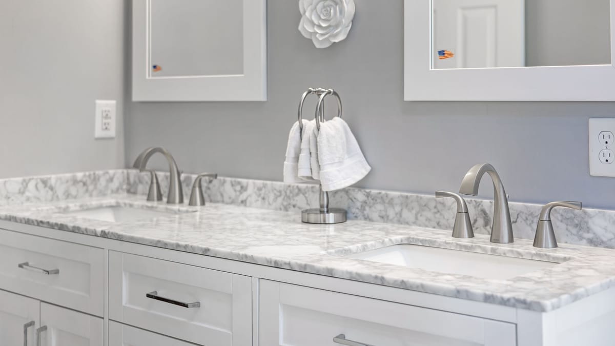 White double bathroom vanity with a marble top and brushed-nickel faucets