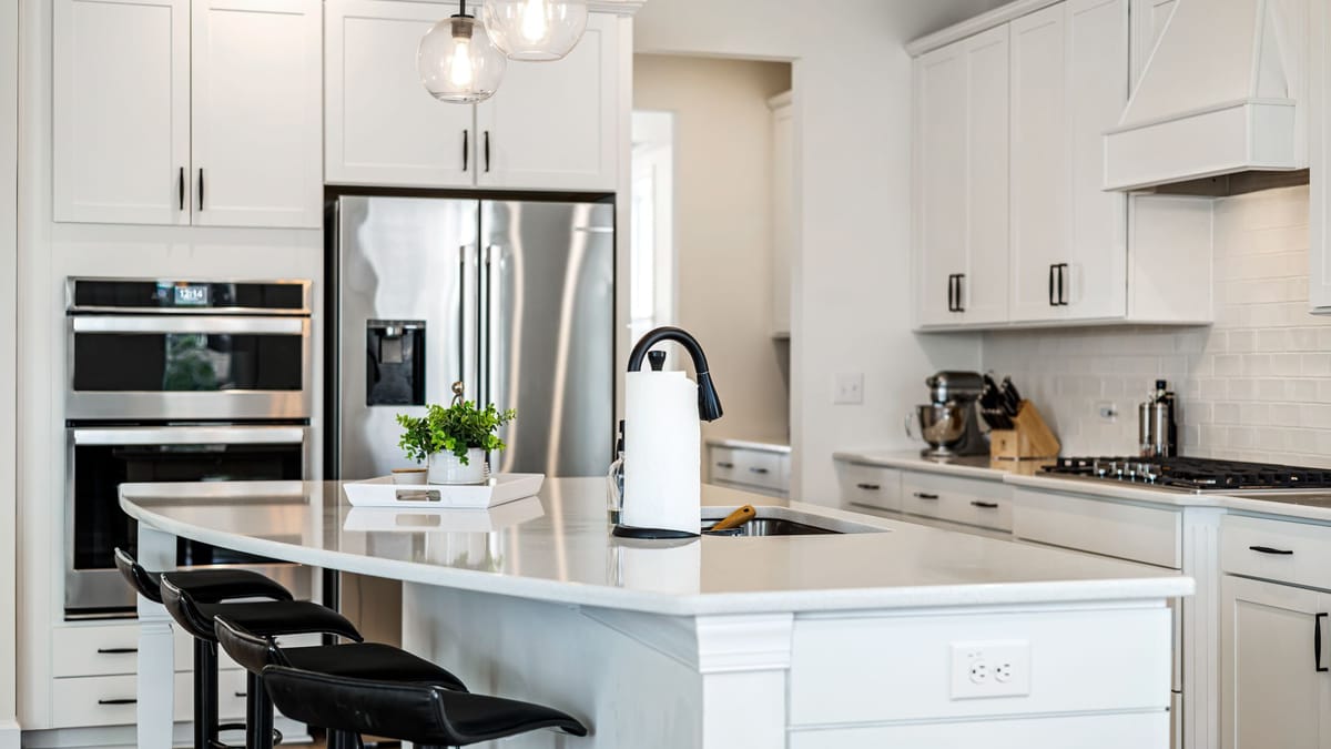 Bright kitchen with white Shaker cabinets, stainless appliances, and a large island with black stools
