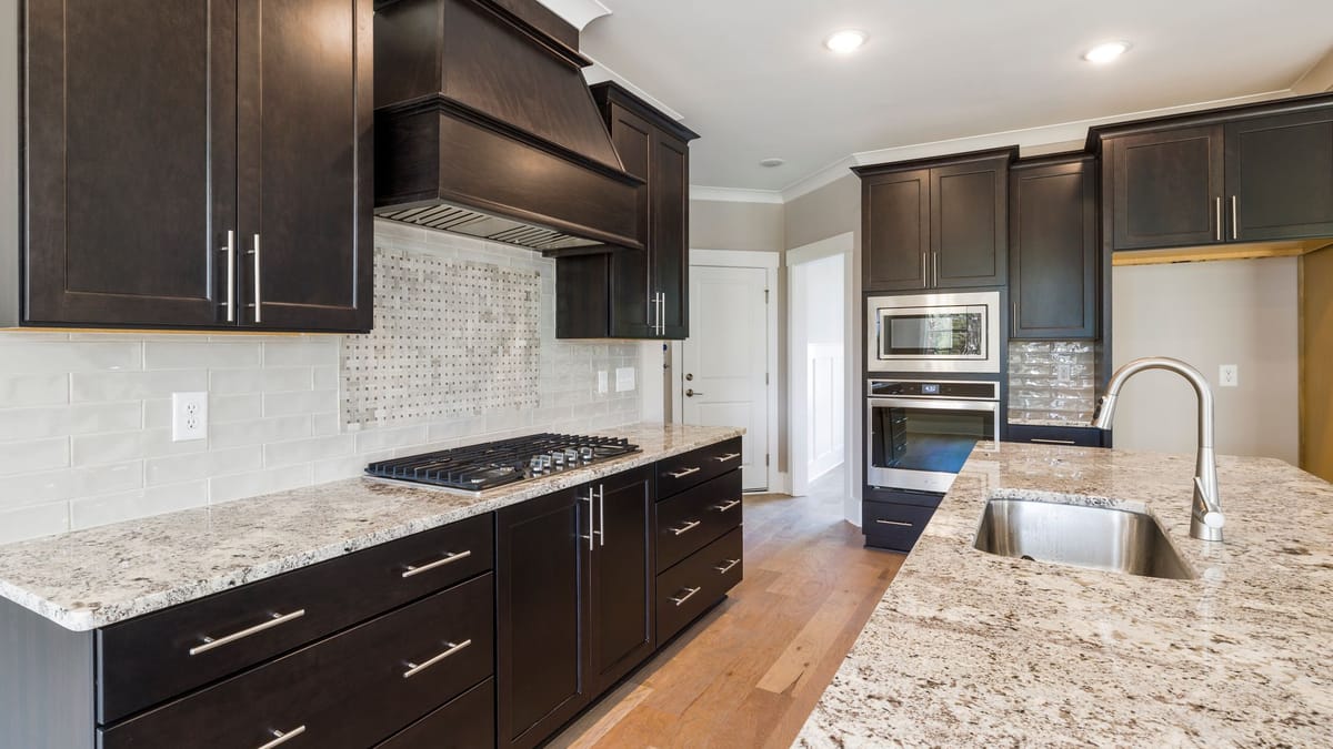 Kitchen with espresso Shaker cabinets, light granite counters, and a dark wood range hood