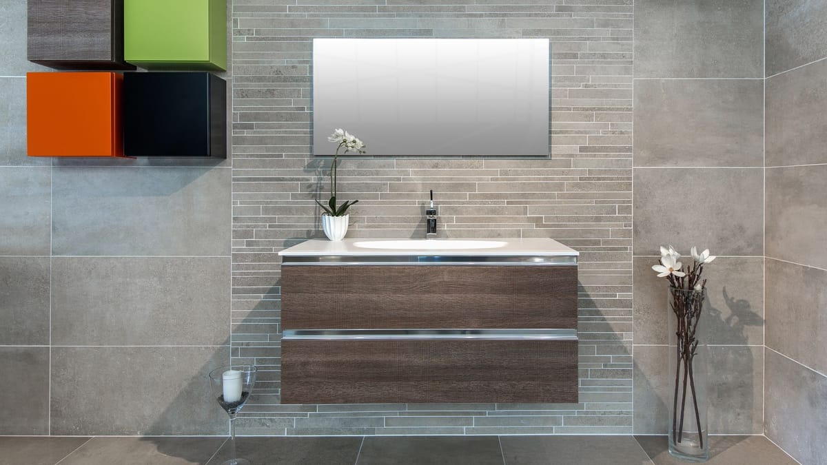 Wall-mounted wood vanity with two drawers and a white basin on a gray tiled wall