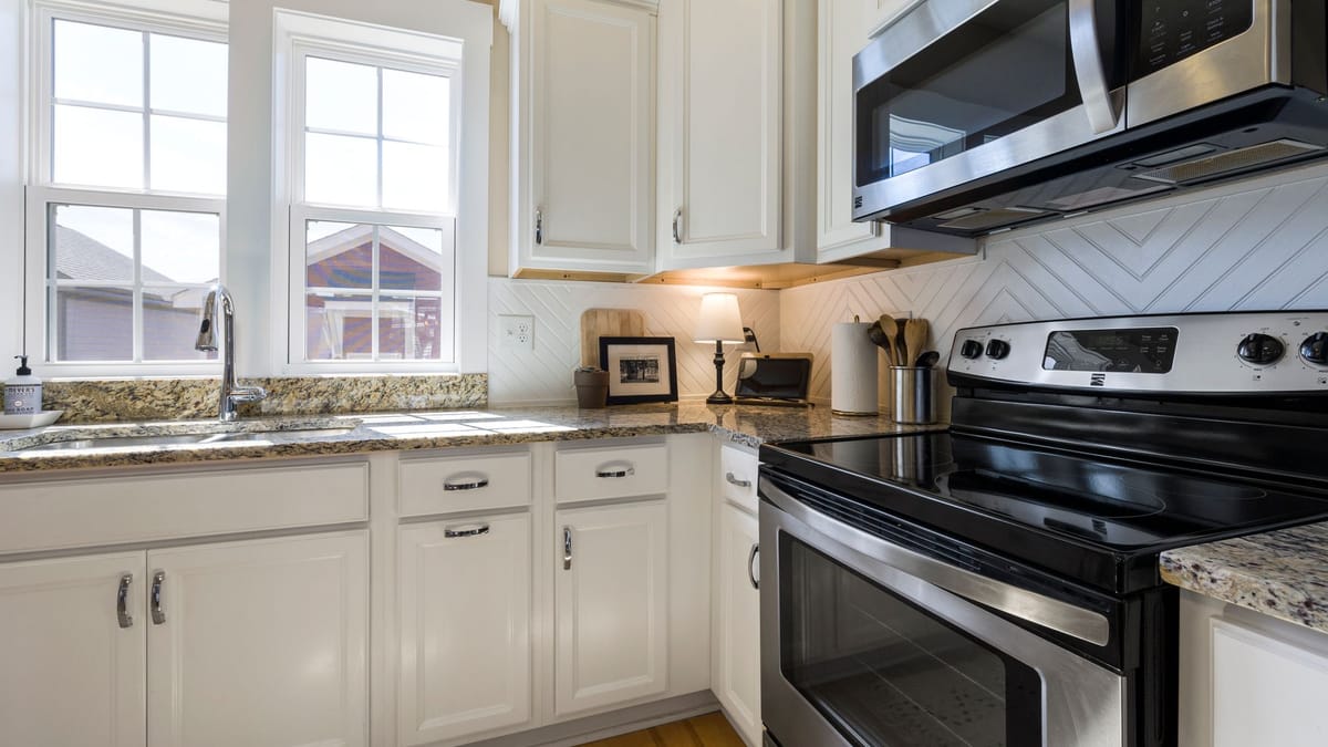 White base cabinets under granite counters, with wall cabinets and a microwave above the range