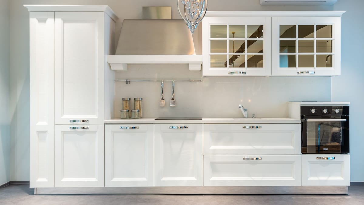 White kitchen with glass-front upper cabinets, a stainless hood, and a tall pantry cabinet