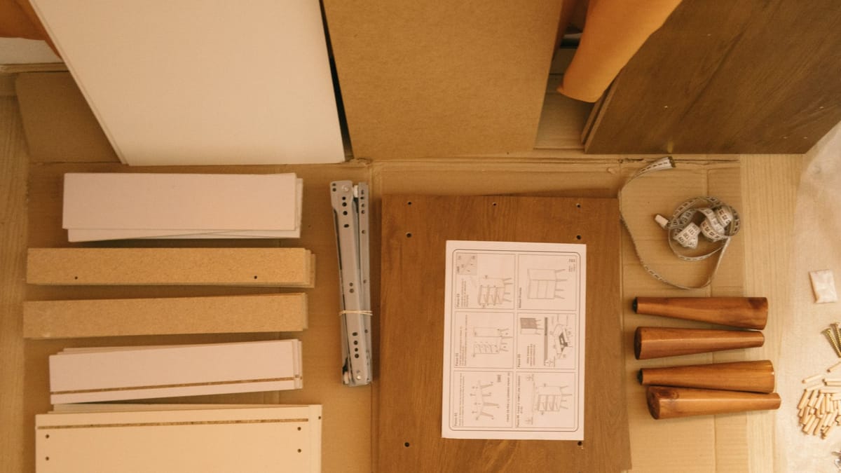 Flat-pack panels, hardware, and an instruction sheet laid out on cardboard before assembly
